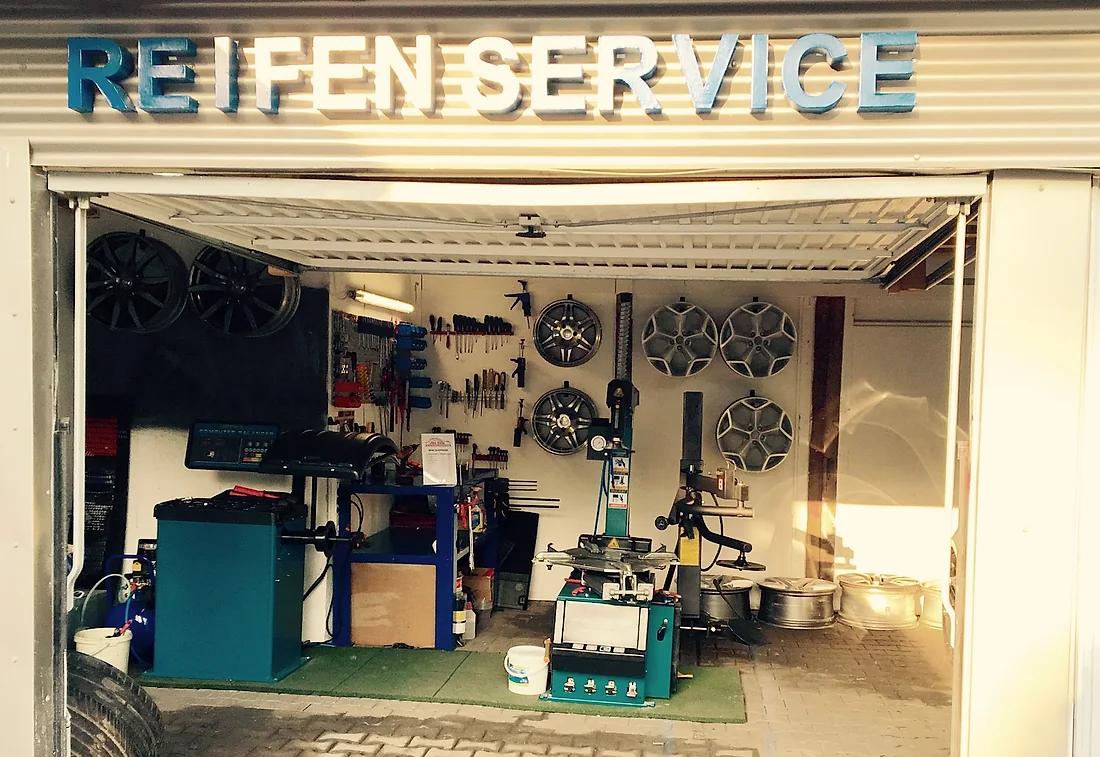 Halle mit Alufelgen an der Wand unter dem Schriftzug Reifen Service