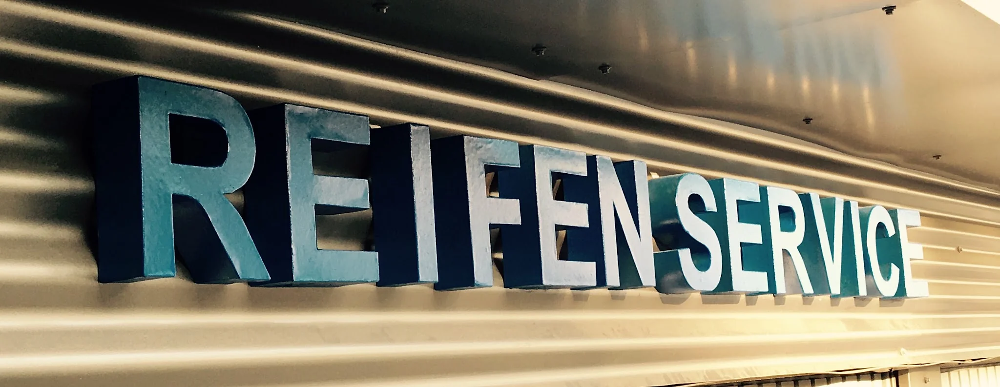 Schriftzug Reifen Service ueber der Werkstatthalle von All Inn Performance